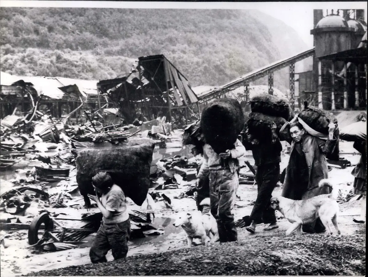 1960-Tausende-sterben-bei-Erdbeben-Arbeiter-und-geborgene-Habseligkeiten-in-Corral-Sch-tzungsweise-mehr-als-dreitausend-Menschen-verloren-bei-der-Erdbebenserie-die-weite-Teile-Chiles-verw-stete-ihr-Leben-Die-Erdbeben-l-sten-Flutwellen-aus-und-zahlreiche-Vulkane-brachen-aus-Foto-Arbeiter-mit-ihrem-einzigen-Hab-und-Gut-in-den-Tr-mmern-von-Corral-Chile-nach-dem-Erdbeben