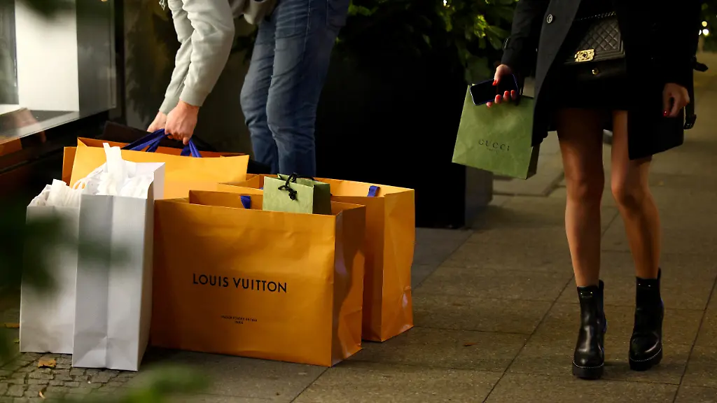 A-woman-stands-next-to-shopping-bags-branded-with-Louis-Vuitton-and-Gucci-outside-the-department-store-Kaufhaus-des-Westens-KaDeWe-in-Berlin-Germany-November-16-2022