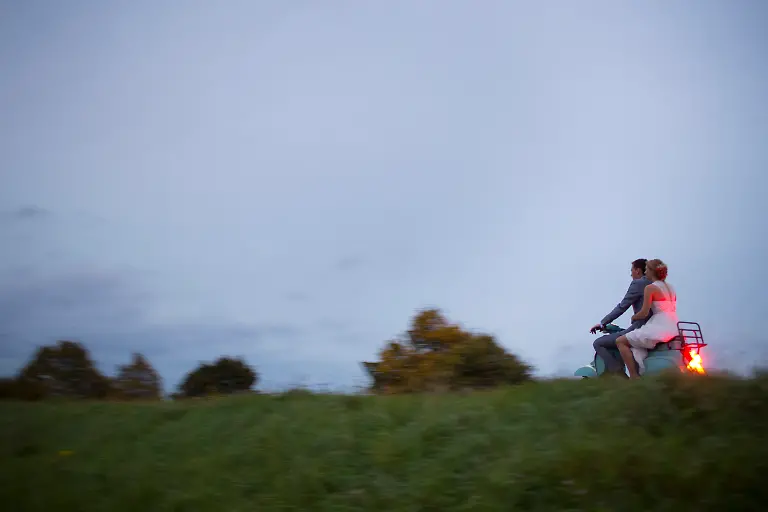 Paar-auf-einem-Motoroller-faehrt-durch-eine-gruene-Landschaft
