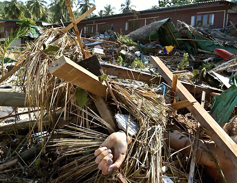 A-hand-sticks-out-under-rubble-on-Phi-Phi-island-Krabi-province-southern-Thailand-Monday-27-December-2004-Hundreds-of-people-were-reported-missing-and-at-least-200-feared-dead-in-Thailand-s-southern-region-as-tidal-waves-battered-the-resort-islands-after-a-massive-earthquake-Sunday-The-official-figures-did-not-include-Phi-Phi-island-one-of-the-hardest-hit-areas-where-thousands-of-tourists-were-stranded-and-hundreds-were-feared-dead