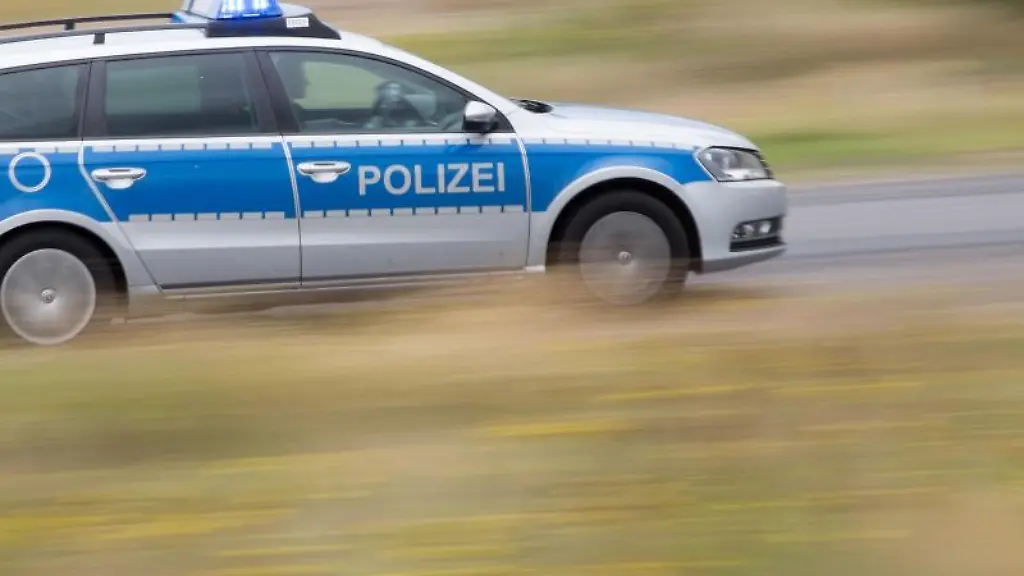 Ein-Streifenwagen-faehrt-mit-Blaulicht-ueber-eine-Strasse