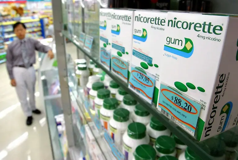epa00155146-epa00155142-A-Singapore-pharmacist-stands-near-boxes-of-Nicorette-chewing-gum-for-sale-in-the-city-state-on-Wednesday-17-March-2004-Singapore-will-officially-lift-part-of-its-famous-ban-on-chewing-gum-on-Thursday-because-of-a-free-trade-agreement-with-the-United-States-but-only-Nicorette-a-gum-made-by-global-pharmaceutal-Pfizer-that-is-aimed-at-helping-smokers-to-quit-will-be-allowed-in-the-Southeast-Asian-island-republic-Some-retailers-have-started-selling-the-therapeutic-gum-early