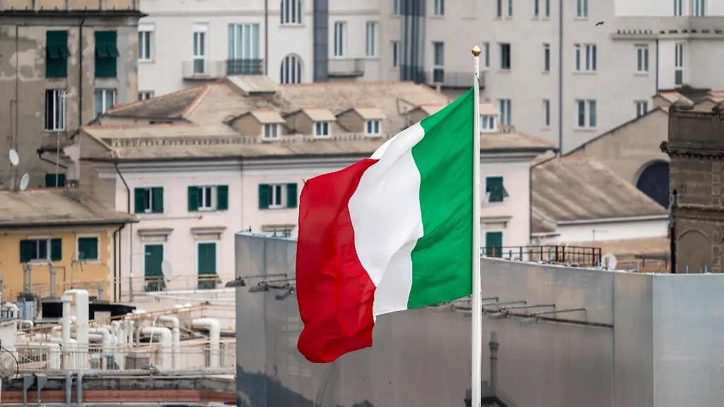 Die-italienische-Nationalflagge-weht-im-Wind-ueber-dem-Hafen-von-Genua