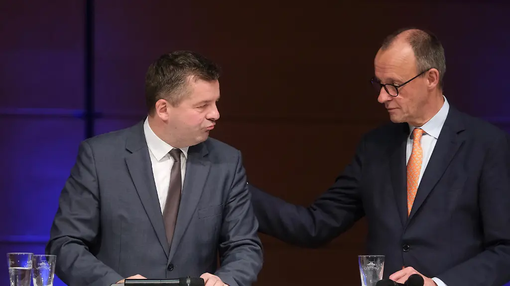 Sven-Schulze-l-CDU-Wirtschaftsminister-des-Landes-Sachsen-Anhalt-und-Bundeskanzler-Friedrich-Merz-CDU-stehen-beisammen-auf-einer-Buehne-Anlass-ist-der-Neujahrsempfang-der-IHK-und-der-Handwerkskammer-Halle-Dessau