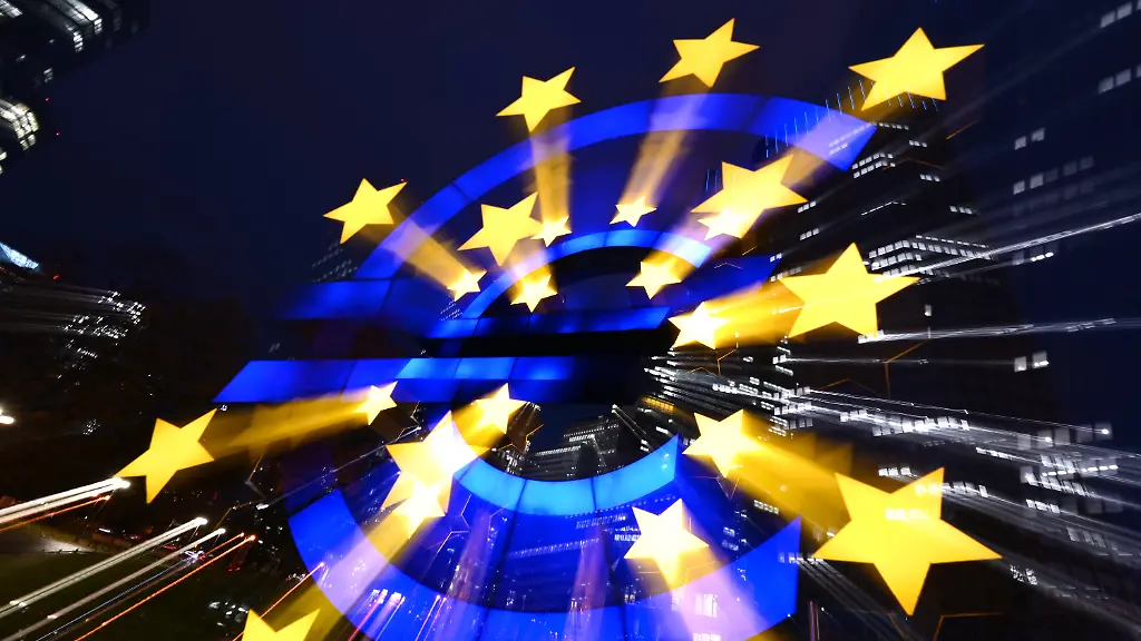 ARCHIV-02-11-2021-Hessen-Frankfurt-Main-Die-Euro-Skulptur-des-Kuenstlers-Ottmar-Hoerl-leuchtet-am-Abend-vor-den-Bankentuermen-Aufnahme-mit-Langzeitbelichtung-und-Zoom-Effekt