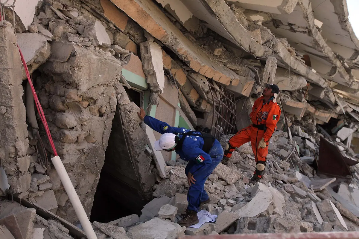 PORT-AU-PRINCE-HAITI-JANUARY-15-Search-and-Rescue-workers-from-Mexico-search-for-a-way-to-reach-survivors-trapped-under-the-rubble-of-what-is-left-of-the-St-Gerard-building-after-the-massive-earthquake-January-15-2010-in-Port-au-Prince-Haiti-Children-could-be-heard-inside-the-building-begging-for-help-Planeloads-of-rescuers-and-relief-supplies-headed-to-Haiti-as-governments-and-aid-agencies-launched-a-massive-relief-operation-after-a-powerful-earthquake-that-may-have-killed-thousands-Many-buildings-were-reduced-to-rubble-by-the-7-0-strong-quake-on-January-12