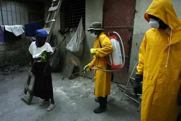 Health-workers-at-a-tent-city-on-the-outskirts-of-Haitian-capital-Port-au-Prince-disinfect-the-house-of-cholera-victim-Alcides-St-Charles-on-November-27-2010-Presidential-campaigning-in-quake-stricken-Haiti-wrapped-up-Saturday-amid-deadly-electoral-violence-concerns-of-voter-fraud-and-a-cholera-outbreak-that-has-yet-to-peak-On-November-28-voters-will-choose-a-successor-to-President-Rene-Preval-who-is-not-running-for-reelection-as-well-as-elect-11-of-the-country-s-30-senators-and-all-99-parliamentary-deputies-in-the-landmark-vote