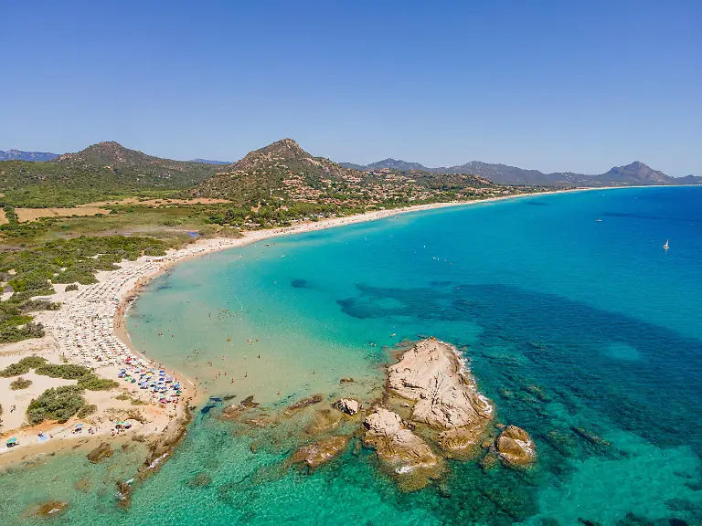 Weisser-Sandstrand-und-tuerkis-blaues-Meer-erstrecken-sich-an-der-Costa-Rei-einem-Kuestenabchnitt-der-italienischen-Mittelmeer-Insel-Sardinien-ueber-mehrere-Kilometer-und-machen-die-Gegend-zu-einem-der-beliebtesten-Urlaubsziele-Europas