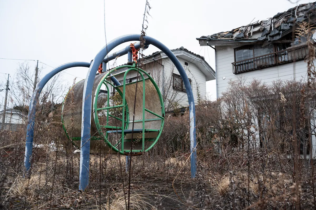 This-photo-taken-on-February-15-2023-shows-an-overgrown-playground-next-to-deserted-buildings-in-the-town-of-Okuma-during-a-government-sponsored-tour-of-the-area-where-the-Fukushima-Daiichi-nuclear-power-plant-is-located-a-few-kilometres-away-along-the-Pacific-coast-in-Fukushima-prefecture-ahead-of-the-12th-anniversary-of-the-March-11-2011-earthquake-and-tsunami-which-hit-the-area-and-crippled-the-plant-Some-11-000-residents-were-forced-to-evacuate-the-town-of-Okuma-following-the-Great-East-Japan-Earthquake-and-Tokyo-Electric-Power-Company-s-TEPCO-Fukushima-Daiichi-nuclear-power-plant-in-March-2011-Evacuation-orders-were-lifted-in-2019-and-2022-respectively-for-nearly-half-the-town-with-a-new-town-hall-commercial-area-and-public-housing-built-for-former-and-new-residents-with-the-hopes-of-attracting-more-people-to-the-region-As-of-December-2022-nearly-400-residents-lived-in-Okuma-with-a-government-target-of-4-000-by-2027-Photo-by-Richard-A
