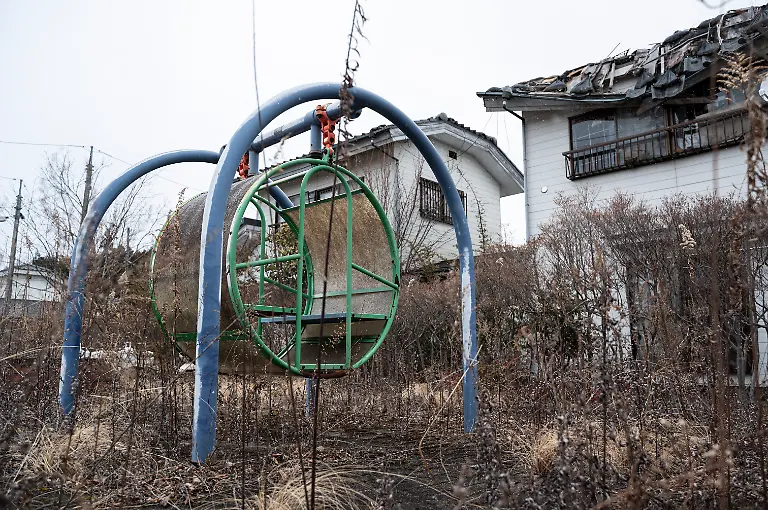 This-photo-taken-on-February-15-2023-shows-an-overgrown-playground-next-to-deserted-buildings-in-the-town-of-Okuma-during-a-government-sponsored-tour-of-the-area-where-the-Fukushima-Daiichi-nuclear-power-plant-is-located-a-few-kilometres-away-along-the-Pacific-coast-in-Fukushima-prefecture-ahead-of-the-12th-anniversary-of-the-March-11-2011-earthquake-and-tsunami-which-hit-the-area-and-crippled-the-plant-Some-11-000-residents-were-forced-to-evacuate-the-town-of-Okuma-following-the-Great-East-Japan-Earthquake-and-Tokyo-Electric-Power-Company-s-TEPCO-Fukushima-Daiichi-nuclear-power-plant-in-March-2011-Evacuation-orders-were-lifted-in-2019-and-2022-respectively-for-nearly-half-the-town-with-a-new-town-hall-commercial-area-and-public-housing-built-for-former-and-new-residents-with-the-hopes-of-attracting-more-people-to-the-region-As-of-December-2022-nearly-400-residents-lived-in-Okuma-with-a-government-target-of-4-000-by-2027-Photo-by-Richard-A