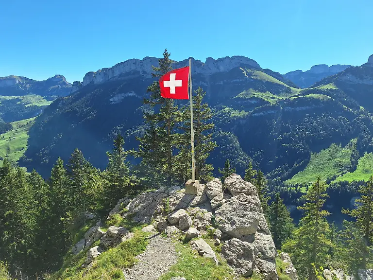 Themenbild-Berggasthaus-Aescher-im-Alpstein-Region-Appenzell-Appenzellerland-Innerrhoden-Bild-Die-schweizer-Nationalflagge-Flagge-weht-im-Wind-Das-beruehmte-Berggasthaus-Aescher-im-Appenzellerland-im-Alpsteinmassiv-im-Kanton-Appenzell