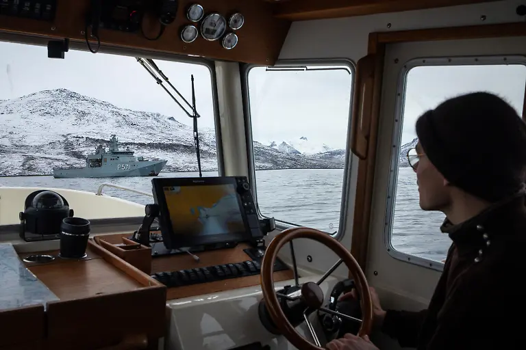 Boat-Captain-Isak-Brandt-sails-past-the-Danish-military-Offshore-Patrol-Vessel-P571-HDMS-Ejnar-Mikkelsen-near-Kapisillit-Greenland-January-21-2026-People-here-are-interested-in-the-day-that-is-coming-Is-there-food-in-the-fridge-Fine-then-I-can-sleep-a-little-longer-If-there-is-no-food-then-I-will-go-out-and-catch-fish-or-go-out-and-shoot-a-reindeer-said-Vanilla-Mathiassen-a-Danish-teacher-in-Kapisillit-who-has-worked-in-towns-and-villages-across-Greenland-for-13-years-REUTERS-Marko-Djurica-SEARCH-DJURICA-GREENLAND-INUIT-FOR-THIS-STORY-SEARCH-WIDER-IMAGE-FOR-ALL-STORIES