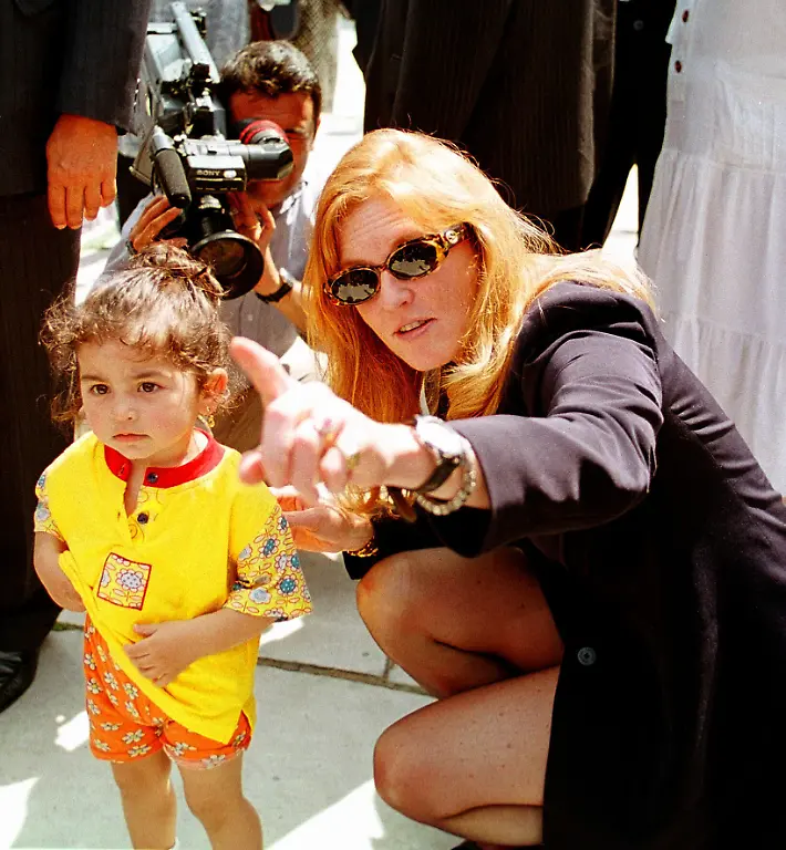 Britain-s-Duchess-of-York-Sarah-Ferguson-points-at-the-cameras-as-she-kneels-beside-a-Turkish-child-during-her-visit-to-the-Blue-Mosque-in-Istanbul-Thursday-June-11-1998-The-former-wife-Britain-s-Duke-of-York-Prince-Andrew-Sarah-Ferguson-was-invited-to-Istanbul-by-Turkish-media-boss-Cem-Uzan