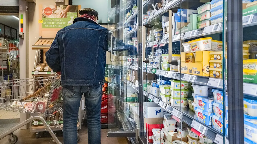 Ein-Kunde-steht-in-einem-Supermarkt-vor-dem-Kuehlregal-mit-Milchprodukten