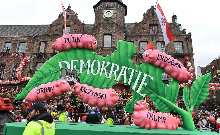 ARCHIV-27-02-2017-Nordrhein-Westfalen-Duesseldorf-Ein-Motivwagen-der-das-Thema-Gefaehrdete-Demokratie-aufgreift-faehrt-im-Rosenmontagsumzug-Von-der-Eintagsfliege-zum-politischen-Dauerbrenner-Jacques-Tillys-Demokratiefresser-Motivwagen-von-vom-Rosenmontag-2017-ist-nach-ueber-einem-Jahr-immer-noch-auf-Tournee-Der-war-jetzt-schon-in-dutzenden-polnischen-Staedten-ich-habe-etwa-30-Artikel-aus-polnischen-Zeitungen-ueber-ihn-gefunden-sagte-Tilly-in-Duesseldorf-der-dpa