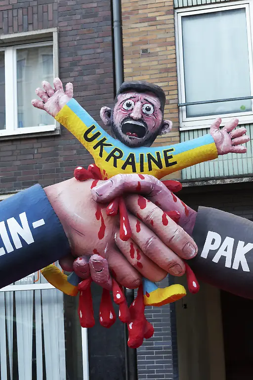 Haendedruck-von-US-Praesident-Donald-Trump-und-Praesident-Wladimir-Putin-zerquetscht-den-ukrainischen-Praesidenten-Selenski-Pappmache-Figur-Mottowagen-von-Jacques-Tilly-Rosenmontagszug-2025-Duesseldorf-Rheinland-Nordrhein-Westfalen-Deutschland-Europa