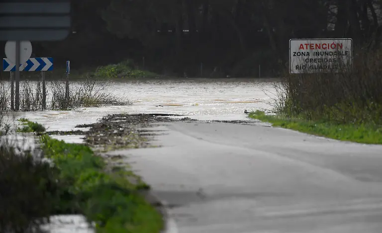 A-sign-reads-Caution-Flood-Prone-Area-Guadalete-River-Floods-as-floodwaters-cover-a-road-at-Las-Pachecas-settlement-in-Jerez-southern-Spain-on-February-5-2026-amid-Storm-Leonardo-Spain-today-lifted-its-highest-weather-alert-for-torrential-rain-in-the-southern-region-of-Andalusia-where-a-woman-went-missing-a-day-after-the-storm-killed-one-in-Portugal-Storm-Leonardo-dumped-more-than-40-centimetres-15-inches-of-rain-in-some-Andalusian-districts-yesterday-forcing-the-evacuation-of-thousands-paralysing-rail-and-road-transport-and-shutting-schools-The-downpours-which-came-after-a-storm-killed-five-people-and-left-hundreds-injured-in-neighbouring-Portugal-last-week-are-examples-of-extreme-weather-that-scientists-say-climate-change-is-worsening