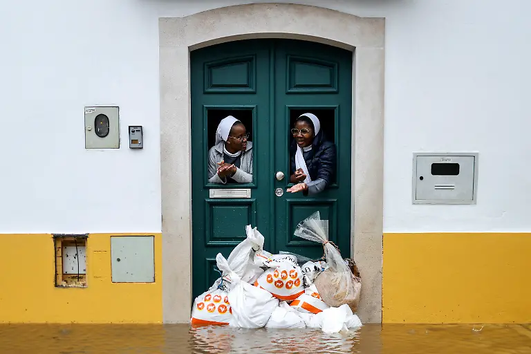 Two-nuns-look-out-from-a-doorway-protected-by-sandbags-as-floodwaters-cover-the-street-in-Alcacer-do-Sal-south-of-Portugal-amid-Storm-Leonardo-on-February-4-2026-A-storm-unleashing-up-to-35-centimetres-14-inches-of-rain-in-24-hours-battered-the-Iberian-Peninsula-today-forcing-thousands-of-people-in-southern-Spain-from-their-homes-shutting-schools-and-cancelling-trains-Leonardo-compounded-difficulties-for-residents-in-Portugal-who-were-already-reeling-from-last-week-s-Storm-Kristin-which-killed-five-people-injured-hundreds-and-cut-off-tens-of-thousands-of-customers-from-the-power-grid