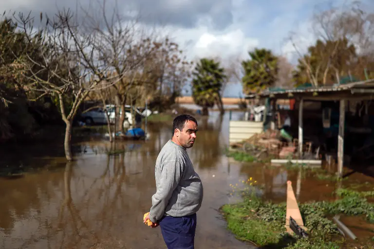 A-man-stands-on-his-flooded-yard-placed-on-a-bank-of-the-Tagus-river-in-the-aftermath-of-Storm-Leonardo-in-the-Portuguese-village-of-Porto-Alto-Benavente-on-February-6-2026-A-deadly-storm-that-triggered-floods-and-thousands-of-evacuations-in-the-Iberian-Peninsula-sparked-calls-yesterday-for-Portugal-s-presidential-run-off-to-be-postponed-but-electoral-officials-insisted-it-would-go-ahead-The-country-of-around-10-million-people-had-barely-recovered-from-last-week-s-battering-by-rain-and-winds-that-killed-five-people-injured-hundreds-and-left-tens-of-thousands-without-power-This-week-s-Storm-Leonardo-has-left-one-dead-in-Portugal-and-lashed-the-southern-Spanish-region-of-Andalusia-where-rescuers-were-searching-for-a-missing-woman-and-evacuated-thousands-of-people