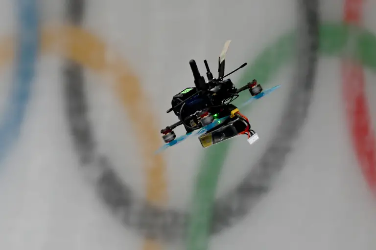 Olympia-Olympische-Winterspiele-Mailand-Cortina-2026-Rodeln-Vorkampf-Einsitzer-Frauen-Durchgang-1-eine-Drohne-fliegt-ueber-den-Eiskanal-mit-den-olympischen-Ringen