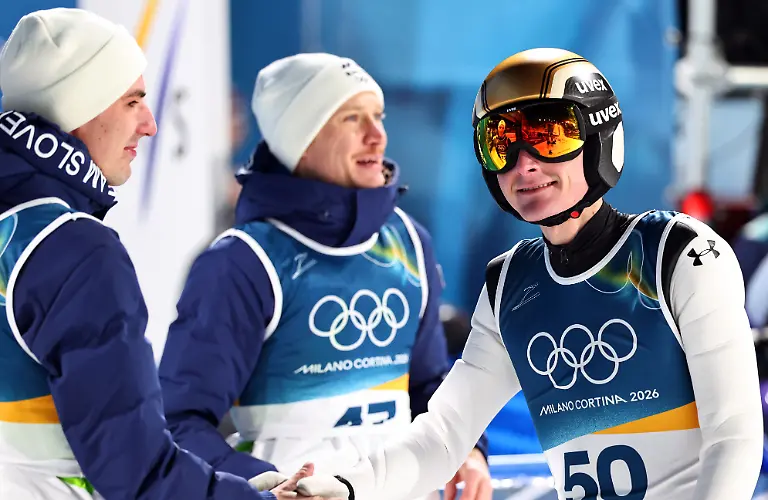 Olympia-Olympische-Winterspiele-Mailand-Cortina-2026-Ski-nordisch-Skispringen-Normalschanze-Maenner-Durchgang-2-Domen-Prevc-r-Slowenien-reagiert-nach-seinem-Sprung-neben-seinen-Teamkollegen