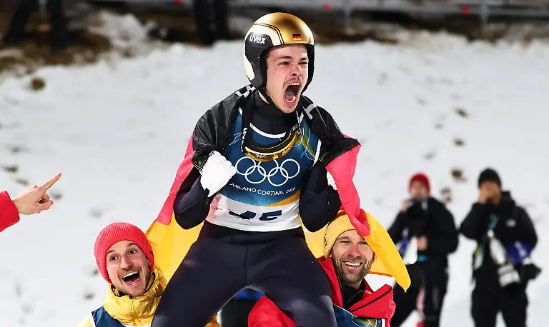 Olympia-Olympische-Winterspiele-Mailand-Cortina-2026-Ski-nordisch-Skispringen-Normalschanze-Maenner-Durchgang-2-Philipp-Raimund-oben-Deutschland-jubelt-mit-den-Teamkollegen-Felix-Hoffmann-l-Deutschland-und-Pius-Paschke-Deutschland-ueber-seinen-Sieg