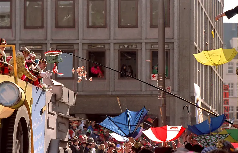 Mit-einem-Korb-an-einer-langen-Stange-angelt-ein-besonders-cleverer-Jeck-am-6-3-2000-beim-Rosenmontagszug-in-Koeln-Bonbons-auf-Koelsch-Kamelle-Andere-spannten-ihre-Schirme-auf-um-die-begehrten-Suessigkeiten-zu-fangen-die-von-den-Karnevalswagen-geworfen-wurden-Zeitweise-strahlender-Sonnenschein-sorgte-fuer-einen-Besucherrekord-Ueber-1-5-Millionen-schunkelnde-und-singende-Narren-feierten-in-Koeln-den-mit-sechs-Kilometern-laengsten-Zoch-Deutschlands-Insgesamt-waren-95-Festwagen-und-128-Musikkapellen-im-Einsatz-Ganz-im-Zeichen-des-Millenniums-lautete-das-diesjaehrige-Motto-Koelle-loss-jonn-ins-neue-Jahrtausend
