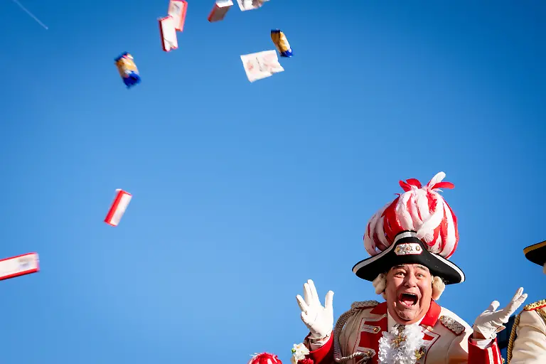 Rote-Funken-wirft-Kamelle-in-die-Menge-auf-dem-Karnevalswagen