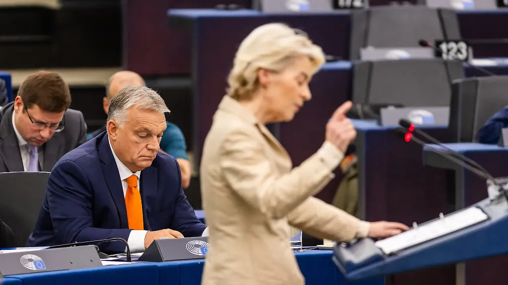 Ursula-von-der-Leyen-CDU-Praesidentin-der-Europaeischen-Kommission-steht-im-Plenarsaal-des-Europaeischen-Parlaments-und-spricht-waehrend-im-Hintergrund-Vikor-Orban-Fidesz-Ministerpraesident-von-Ungarn-zu-sehen-ist-Zu-Beginn-des-dritten-Sitzungstags-will-Ungarns-Regierungschef-Orban-die-Arbeit-der-ungarischen-EU-Ratspraesidentschaft-vorstellen-Zudem-soll-ueber-nachhaltigen-menschenwuerdigem-und-bezahlbaren-Wohnraum-in-der-EU-diskutiert-werden-Anschliessend-besprechen-die-Abgeordneten-Faelle-von-Verletzungen-der-Menschenrechte-der-Demokratie-und-der-Rechtsstaatlichkeit