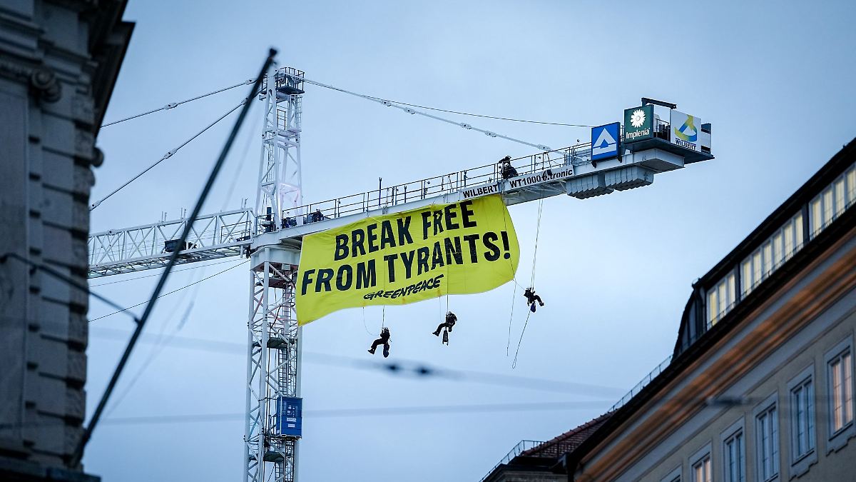 Kletterer entrollen Protest-Transparent an Kran in München