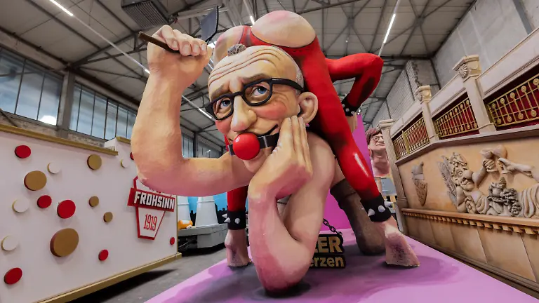 Ein-Motivwagen-fuer-den-Koelner-Rosenmontagszug-der-Bundeskanzler-Merz-und-Finanzminister-Klingbeil-bei-einer-Sado-Maso-Regierungs-Show-zeigen-wird-beim-Richtfest-in-der-Wagenbauhalle-praesentiert