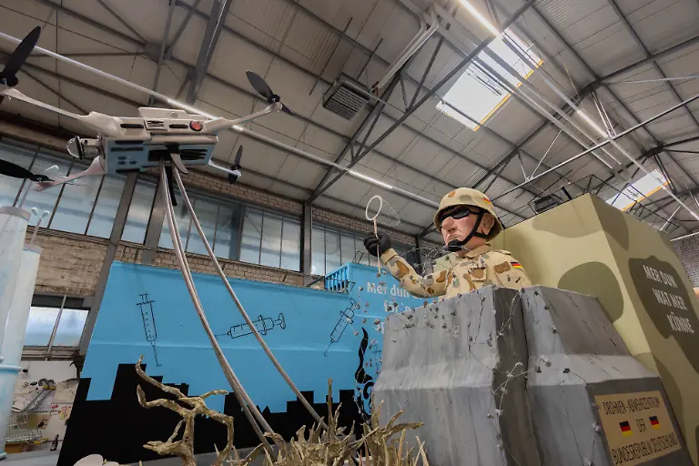 Ein-Motivwagen-fuer-den-Koelner-Rosenmontagszug-der-sich-mit-dem-Thema-Drohnenabwehr-auseinandersetzt-zeigt-einen-Bundeswehrsoldaten-der-mit-einem-Kescher-eine-Drohne-fangen-will-beim-Richtfest-in-der-Wagenbauhalle