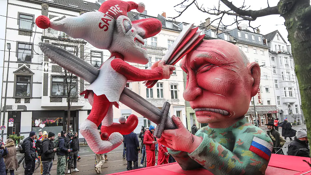 Mottowagen-des-Duesseldorfer-Bildhauers-Jacques-Tilly-am-Montag-16-02-2026-auf-dem-Duesseldorfer-Rosenmontagszug-Foto-Der-russische-Praesident-Wladimir-Putin-spiesst-den-Hoppeditz-mit-einem-Schwert-auf-Die-Duesseldorfer-Karnevalsfigur-wiederum-schlaegt-dem-in-Militaeruniform-gekleideten-Putin-mit-einer-Narrenpritsche-auf-den-Kopf-In-Moskau-laeuft-aktuell-ein-Prozess-gegen-den-Wagenbauer-Tilly-wegen-Verunglimpfung-der-russischen-Staatsorgane-Tilly-nimmt-nicht-an-dem-Verfahren-in-Russland-teil-Siehe-epd-Meldung-vom-16-02