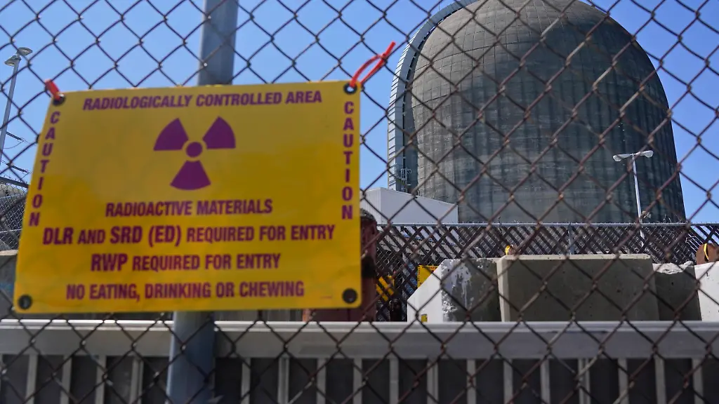FILE-In-this-April-26-2021-photo-a-sign-on-a-fence-warns-of-radioactive-materials-at-a-containment-building-housing-a-nuclear-reactor-at-the-Indian-Point-nuclear-power-plant-in-Buchanan-N-Y-State-regulators-approved-a-deal-Wednesday-May-19-2021-clearing-the-way-to-decommission-the-recently-idled-plant-north-of-New-York-City-The-state-Public-Service-Commission-approved-the-transfer-of-the-plant-from-Entergy-Corp-to-Holtec-International-subsidiaries-according-to-Gov-Andrew-Cuomo-Opponents-said-the-plant-was-a-safety-threat-to-millions-in-the-densely-packed-metropolitan-region