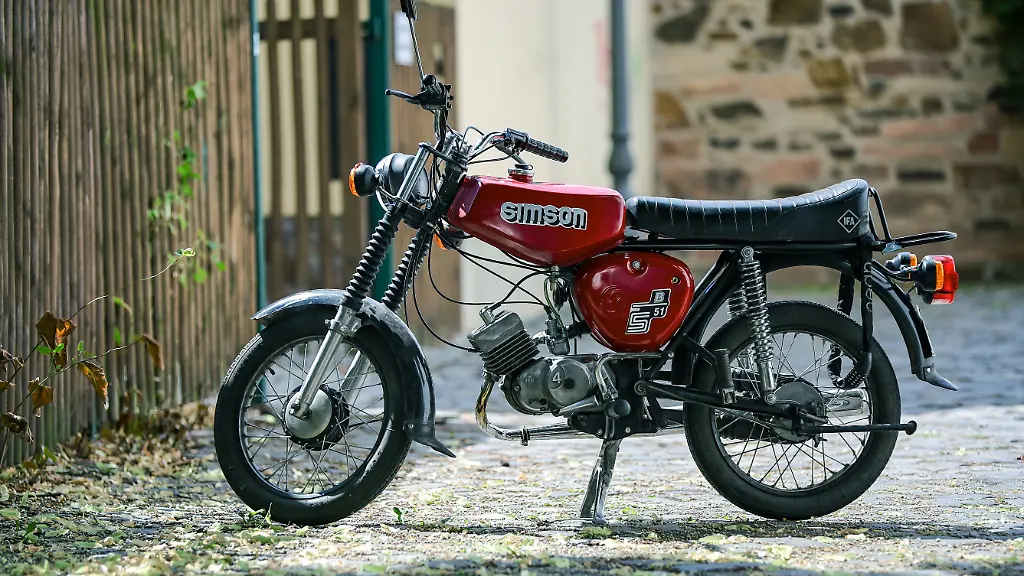 Ein-Moped-S51-B-der-Marke-Simson-steht-in-einem-Hinterhof-Das-mit-einem-Zweitaktmotor-angetriebene-Moped-wurde-zwischen-1980-und-1990-ueber-1-6-Millionen-gebaut-Durch-eine-Ausnahmeregelung-im-Einheitsvertrag-kann-das-Fahrzeug-trotz-einer-Hoechstgeschwindigkeit-von-60km-h-mit-dem-Mopedfuehrerschein-gefahren-werden-Das-erklaert-seine-anhaltende-Beliebtheit-auch-ueber-30-Jahre-nach-Produktionsende