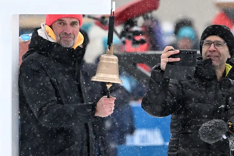 Olympia-Olympische-Winterspiele-Mailand-Cortina-2026-Biathlon-Maenner-Staffel-4-x-7-5-Kilometer-in-der-Anterselva-Biathlon-Arena-der-ehemalige-Fussball-Trainer-Juergen-Klopp-l-steht-an-der-Glocke-neben-dem-frueheren-Biathleten-Ole-Einar-Bjoerndalen-r