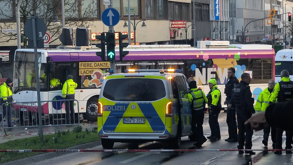 Polizisten-stehen-an-einer-Unfallstelle-Beim-Karnevalsumzug-in-Moenchengladbach-ist-eine-Frau-unter-einen-Bus-geraten-und-verletzt-worden-Die-Frau-sei-ins-Krankenhaus-gebracht-worden-sagte-eine-Polizeisprecherin-auf-dpa-Anfrage-Ihr-Zustand-sei-kritisch