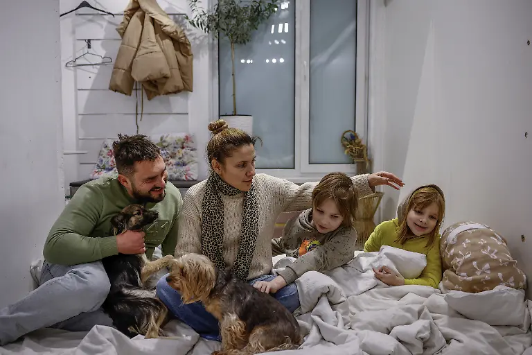 The-Davydenko-family-from-left-to-right-Denys-40-Yuliia-40-and-their-children-Maksym-11-Tymofiy-6-and-Stephanie-2-pose-for-a-picture-on-an-improvised-bed-on-the-floor-of-their-cafe-where-they-are-staying-because-their-apartment-has-no-heating-or-hot-water-and-faces-frequent-power-outages-amid-Russia-s-attack-on-Ukraine-in-Kyiv-Ukraine-February-1-2026-Waves-of-Russian-attacks-over-the-past-four-months-left-hundreds-of-thousands-without-electricity-and-water-making-this-the-most-devastating-winter-since-the-war-started-and-so-the-Davydenko-family-made-the-choice-to-stay-at-the-family-owned-Piggy-Cafe-Kyiv-with-power-supplied-by-a-generator-and-heating-Maksym-likes-it-the-father-Denys-Davydenko-40-joked-about-their-new-reality-He-actually-says-that-at-home-we-have-to-do-household-chores-Now-there-s-no-dish-washing-cleaning-walking-the-dogs-So-he-is-happy-about-that-REUTERS-Alina-Smutko-SEARCH-SMUTKO-COLD-FAMILY-FOR-THIS-STORY-SEARCH-WIDER-IMAGE-FOR-ALL-STORIES