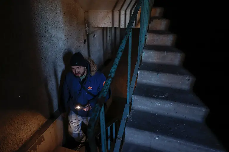 Denys-Davydenko-40-uses-a-flashlight-to-climb-a-stairwell-to-his-family-s-12th-floor-apartment-which-has-no-heating-or-hot-water-and-experiences-frequent-power-outages-amid-Russia-s-attack-on-Ukraine-in-Kyiv-Ukraine-February-2-2026-Waves-of-Russian-attacks-over-the-past-four-months-left-hundreds-of-thousands-without-electricity-and-water-making-this-the-most-devastating-winter-since-the-war-started-and-so-the-Davydenko-family-made-the-choice-to-stay-at-the-family-owned-Piggy-Cafe-Kyiv-with-power-supplied-by-a-generator-and-heating-Maksym-likes-it-Denys-joked-about-their-new-reality-He-actually-says-that-at-home-we-have-to-do-household-chores-Now-there-s-no-dish-washing-cleaning-walking-the-dogs-So-he-is-happy-about-that-REUTERS-Alina-Smutko-SEARCH-SMUTKO-COLD-FAMILY-FOR-THIS-STORY-SEARCH-WIDER-IMAGE-FOR-ALL-STORIES