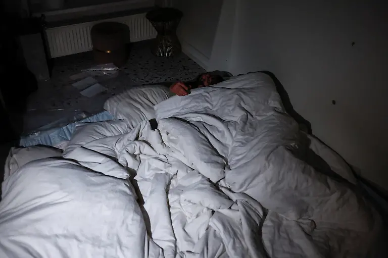 Denys-Davydenko-40-and-his-children-Maksym-11-Tymofiy-6-and-Stephanie-2-sleep-on-an-improvised-bed-on-the-floor-of-their-cafe-where-they-are-staying-because-their-apartment-has-no-heating-or-hot-water-and-faces-frequent-power-outages-amid-Russia-s-attack-on-Ukraine-in-Kyiv-Ukraine-February-1-2026-Waves-of-Russian-attacks-over-the-past-four-months-left-hundreds-of-thousands-without-electricity-and-water-making-this-the-most-devastating-winter-since-the-war-started-and-so-the-Davydenko-family-made-the-choice-to-stay-at-the-family-owned-Piggy-Cafe-Kyiv-with-power-supplied-by-a-generator-and-heating-Maksym-likes-it-Denys-joked-about-their-new-reality-He-actually-says-that-at-home-we-have-to-do-household-chores-Now-there-s-no-dish-washing-cleaning-walking-the-dogs-So-he-is-happy-about-that-REUTERS-Alina-Smutko-SEARCH-SMUTKO-COLD-FAMILY-FOR-THIS-STORY-SEARCH-WIDER-IMAGE-FOR-ALL-STORIES
