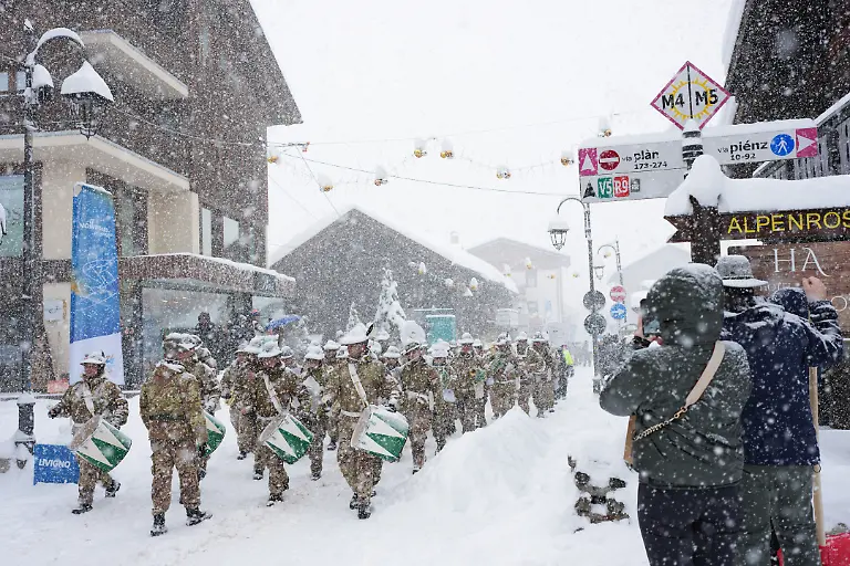 Das-Musikkorps-Fanfara-Alpina-Sezione-Valtellinese-tritt-nach-wetterbedingten-Verzoegerungen-bei-den-Olympischen-Winterspielen-Mailand-Cortina-2026-bei-starkem-Schneefall-auf-und-zieht-durch-den-Ort