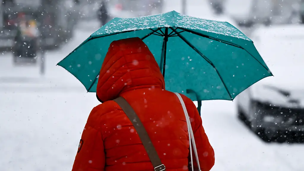 Eine-Frau-geht-mit-einem-Regenschirm-auf-einem-Gehweg-entlang