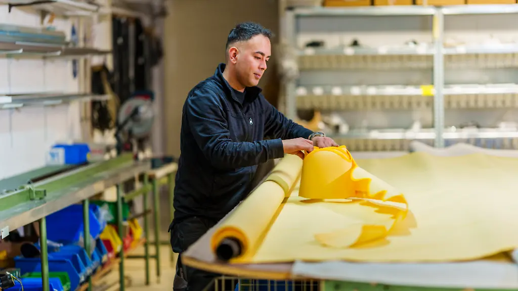 Siawash-Osmani-Rollladen-und-Sonnenschutztechnikermeister-und-Geschaeftsfuehrer-der-Marucci-Markisen-GmbH-rollt-in-der-Werkstatt-einen-Markisenabschluss-Volant-auf-Osmani-ist-aus-Afghanistan-nach-Deutschland-gefluechtet-und-hat-sich-hier-eine-erfolgreiche-Existenz-aufgebaut-Osmani-wurde-im-vergangenen-Jahr-eingebuergert-und-darf-nun-bei-der-Bundestagswahl-am-23-Februar-erstmals-mit-28-Jahren-mit-ueber-ein-Parlament-bestimmen