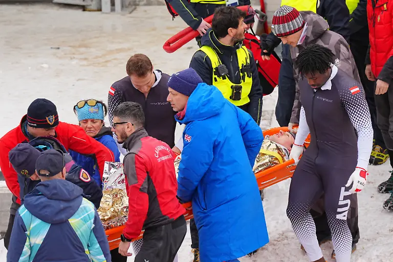 Olympia-Olympische-Winterspiele-Mailand-Cortina-2026-Bob-Viererbob-Maenner-Lauf-2-im-Cortina-Sliding-Centre-Pilot-Jakob-Mandlbauer-wird-nach-einem-Unfall-von-Teamgefaehrten-medizinischen-Betreuern-und-Sicherheitspersonal-von-der-Bahn-getragen