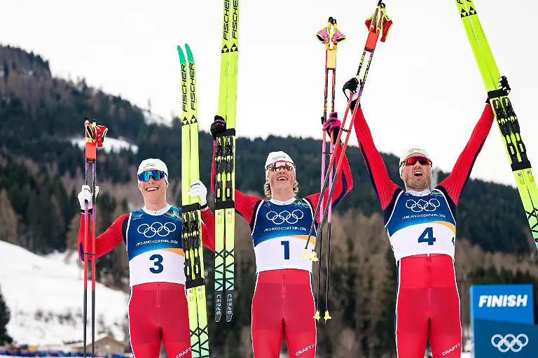 260221-Emil-Iversen-Johannes-Høsflot-Klæbo-and-Martin-Løwstroem-Nyenget-of-Norway-celebrate-after-competing-in-the-men-s-50km-classic-technique-cross-country-skiing-race-during-day-15-of-the-2026-Winter-Olympics-on-February-21-2026-in-Val-di-Fiemme