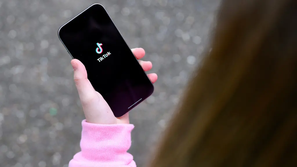 A-teenager-poses-for-a-picture-with-a-phone-displaying-the-TikTok-logo-in-Bonn-Germany-February-20-2026