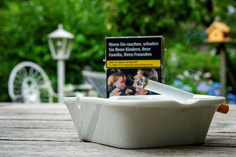 BGH-verhandelt-zum-Verkauf-von-Zigarettenpackungen-mit-Schockbildern-an-Ausgabeautomaten-an-Supermarktkassen-Vor-einer-Zigarettenschachtel-steckt-eine-qualmende-Zigarette-in-einem-Aschenbecher