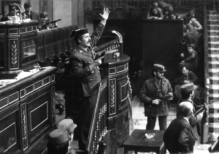 Mit-gezogener-Pistole-steht-der-Putschist-Antonio-Tejero-Molina-gestikulierend-am-Rednerpult-im-spanischen-Parlament-Der-Oberstleutnant-stuermte-damals-mit-mehr-als-200-Mann-der-paramilitaerischen-Guardia-Civil-das-Parlamentsgebaeude-in-Madrid-und-nahm-die-Abgeordneten-mitsamt-der-Regierung-als-Geiseln-Durch-den-Einsatz-von-Koenig-Juan-Carlos-fuer-die-demokratische-Ordnung-brach-der-Putschversuch-nach-18-Stunden-zusammen