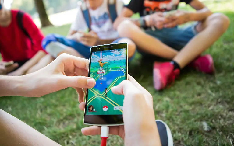 Jugendliche-spielen-in-einem-Park-Pokemon-GO-auf-ihren-Smartphones-Das-Pokemon-Go-Festival-startet-am-Donnerstag-in-Dortmund-Vier-Tage-koennen-Fans-Jagd-auf-die-kleinen-virtuellen-Monster-machen-Nach-grossem-Zulauf-in-der-Ruhrgebietsstadt-vor-einem-Jahr-plant-der-US-amerikanische-Mobilspiel-Entwickler-Niantic-diesmal-ein-europaeisches-XL-Event