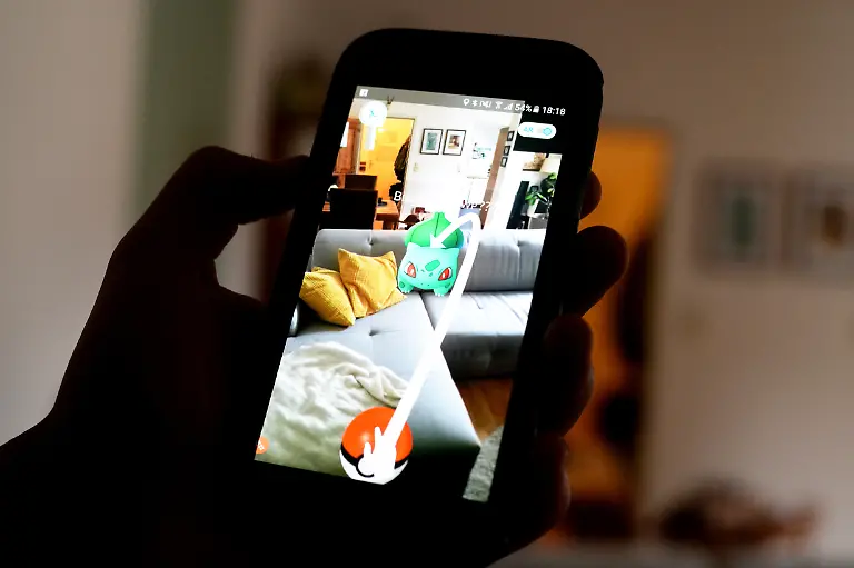 ILLUSTRATION-Ein-Pokemon-Go-Spieler-zeigt-am-13-07-2016-in-Berlin-sein-Smartphone-auf-dem-zu-sehen-ist-wie-das-Pokemon-Bisasam-gemuetlich-auf-der-Couch-sitzt-Das-Spiel-basiert-auf-echten-Geodaten-und-fuehrt-seine-Teilnehmer-per-GPS-von-Ort-zu-Ort-Auch-in-der-eigenen-Wohnung-verstecken-sich-die-Spielfiguren